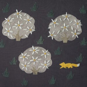 Hand embroidery of a yellow fox walking past three stylized flowering trees on dark grey fabric.