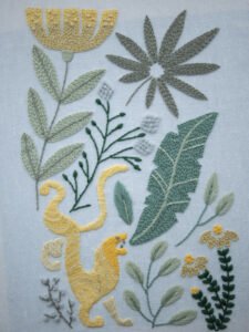Angled close-up of the "Rousseau's Jungle" embroidery, focusing on the details of a yellow monkey and surrounding tropical plants.