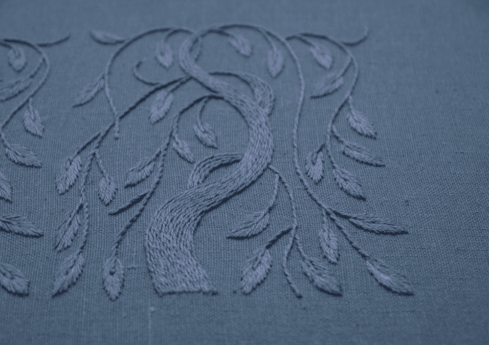 An angled view of a single hand-stitched weeping willow, showcasing the intricate threadwork and serene monochromatic color palette.