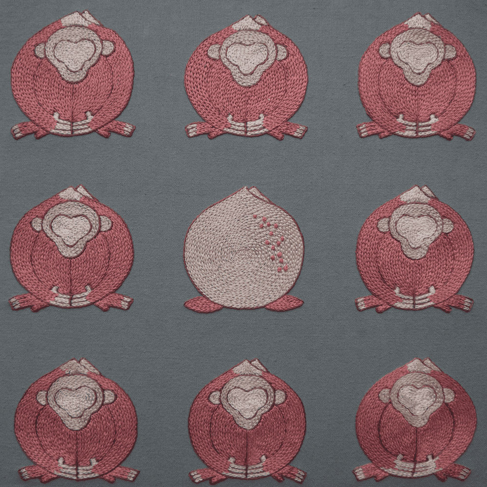Hand-embroidered artwork titled Embracing Loneliness, featuring nine peach-shaped monkeys in pink on grey linen. The central figure is a different color and faces away, symbolizing individuality.