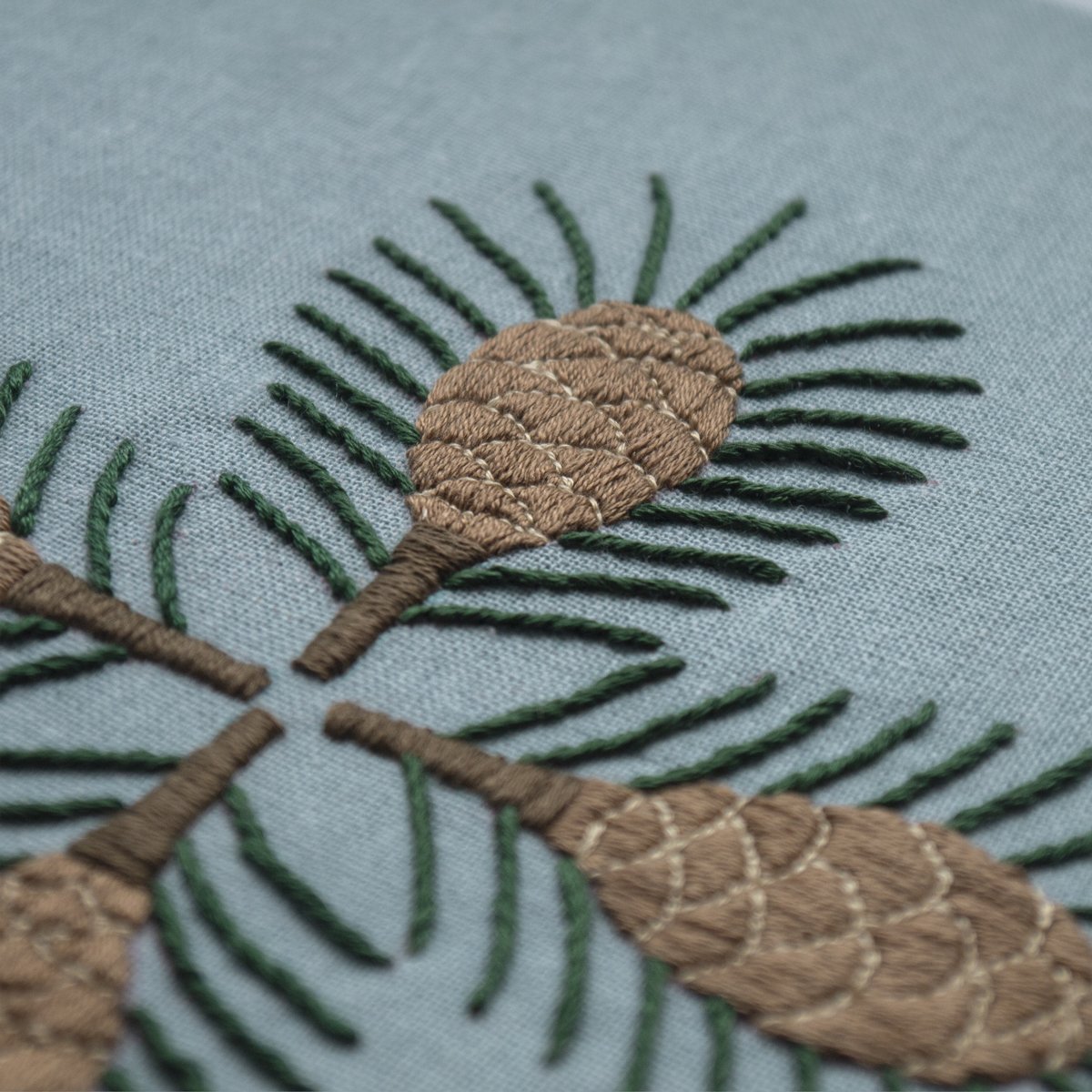 An angled, close-up view of the symmetrical "Pine" embroidery, with the foreground in sharp focus to emphasize the thread detail.