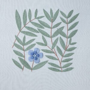 A finished hand embroidery piece featuring a modern botanical pattern with a single blue flower and sage green leaves on a light fabric background.