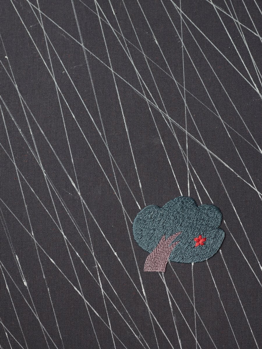 Detail of 'Shelter from the Rain' embroidery, showing the small blue tree against the texture of the pink, slanting rain stitches.