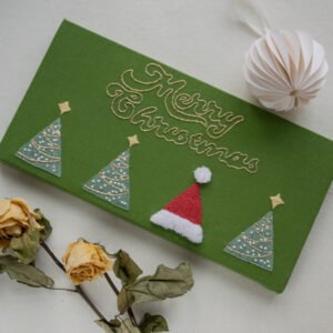 Framed hand-embroidered Christmas wall decor (15x30cm) with 'Merry Christmas' in gold thread, three trees, and a red Santa hat on a green fabric background.
